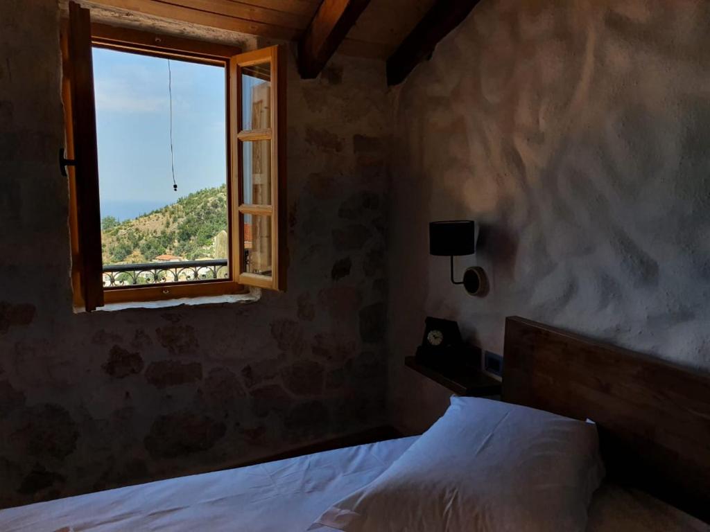 a bedroom with a bed and a window at Roots Dhermi in Dhërmi