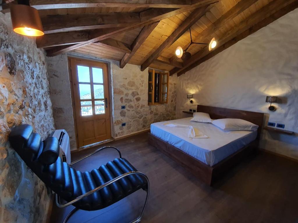 een slaapkamer met een bed en een stoel in een kamer bij Roots Dhermi in Dhërmi