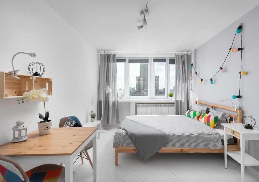 a white bedroom with a bed and a desk at Bagno Cozy Studio II in Warsaw