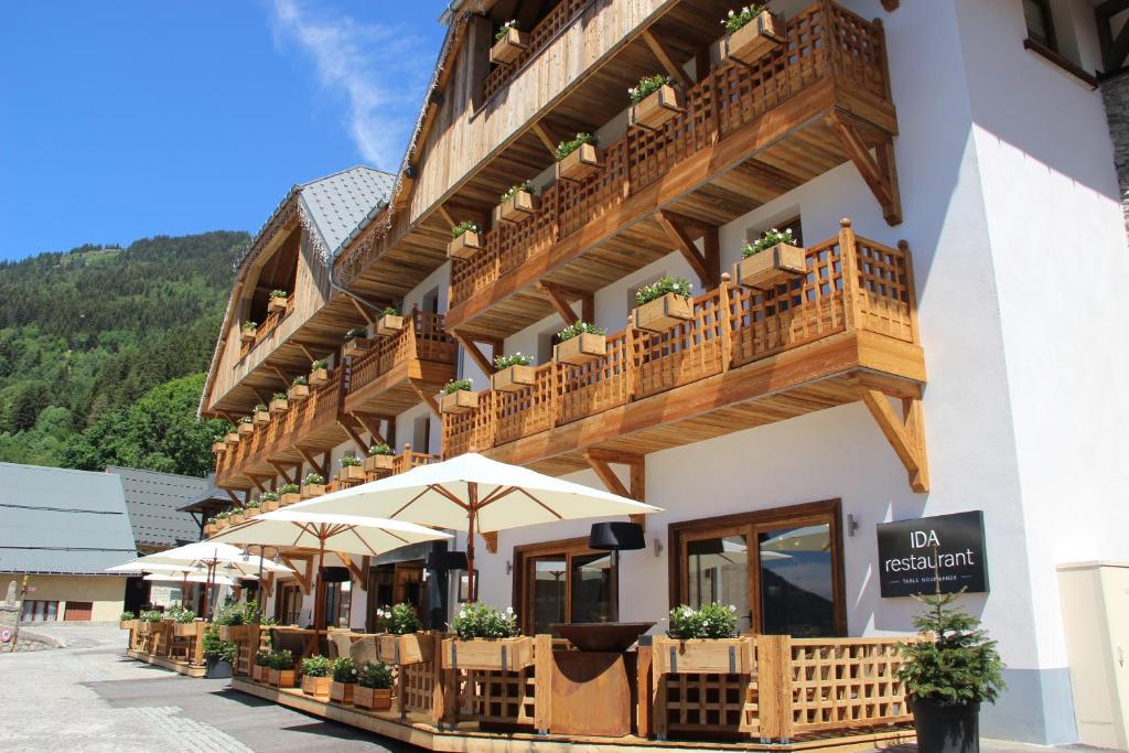 a building with tables and umbrellas in front of it at Hotel Le V de Vaujany in Vaujany