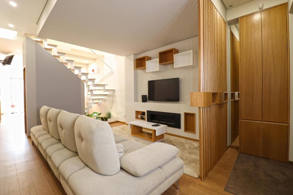 a living room with a white couch and a tv at Ribeira Riverhouse - City Centre Duplex with Terrace in Viana do Castelo