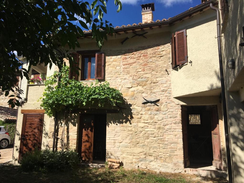 une vieille maison en pierre avec un arbre en face de celle-ci dans l'établissement Antica Quercia B&B, à Pievebovigliana