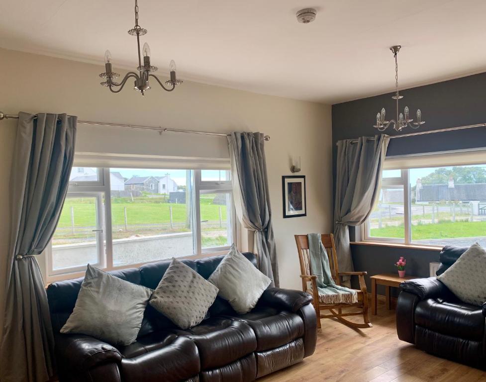 a living room with a leather couch and windows at Wild Atlantic Way Cottage in Achill