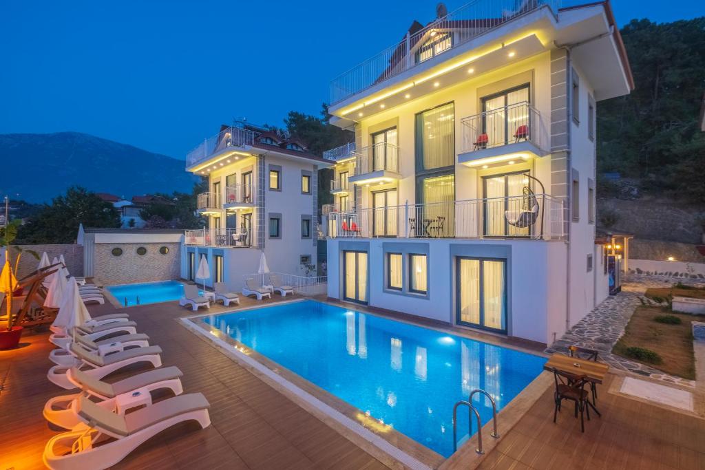 a villa with a swimming pool in front of a building at Monastery Suites Hotel in Oludeniz