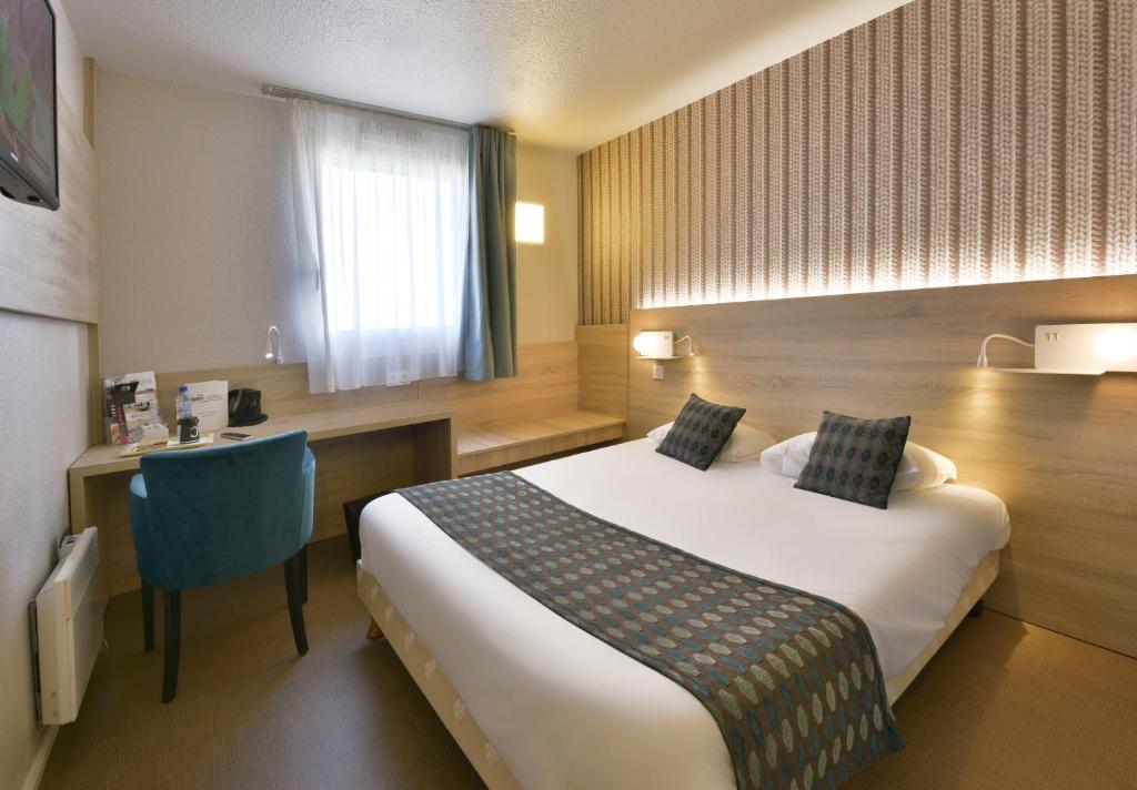 a hotel room with a bed and a desk at Brit Hotel Landivisiau in Landivisiau