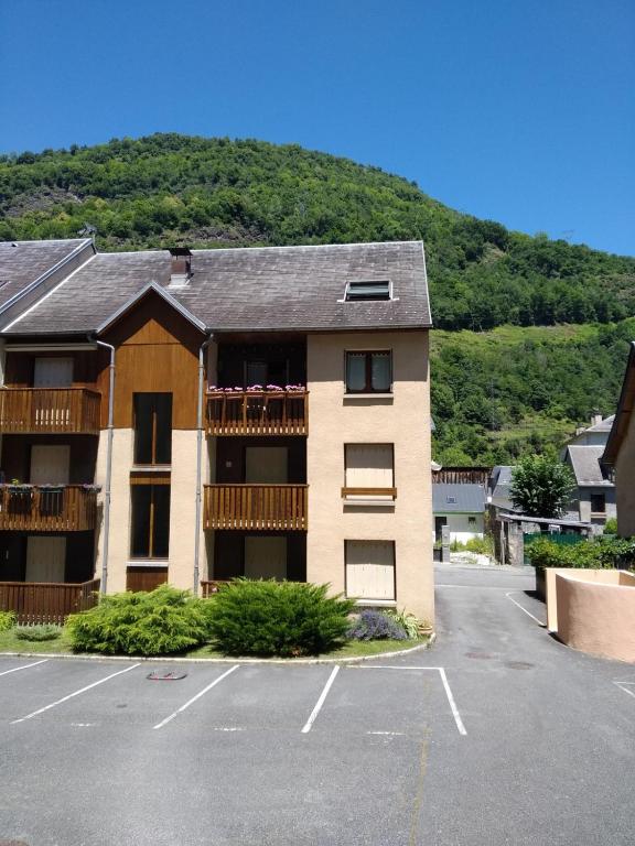un immeuble d'appartements avec un parking en face d'une montagne dans l'établissement Résidence Peyresourde, à Luchon
