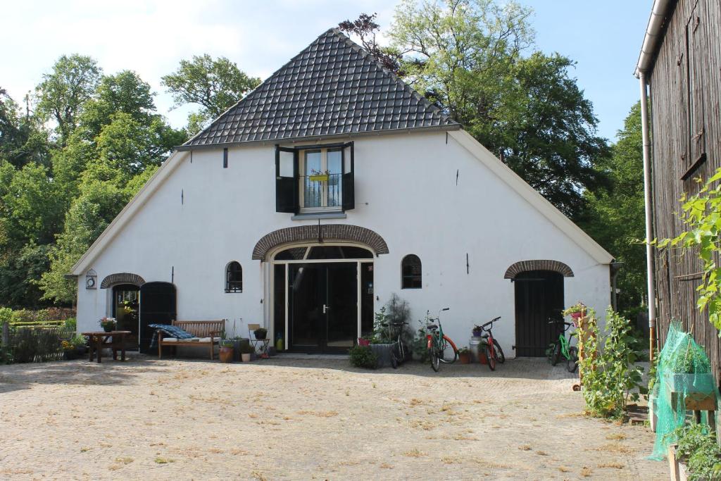 une grange blanche avec un toit noir dans l'établissement Hoeve Op Vollenhof, à Wezep