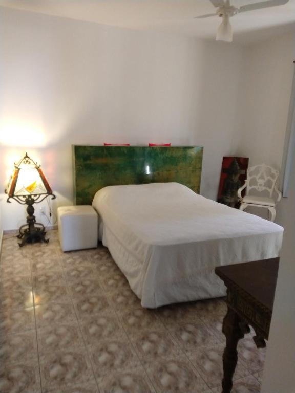 a bedroom with a bed and a table and a lamp at Casa da Lili-ESPAÇO INDEPENDENTE E PRIVATIVO in Brotas
