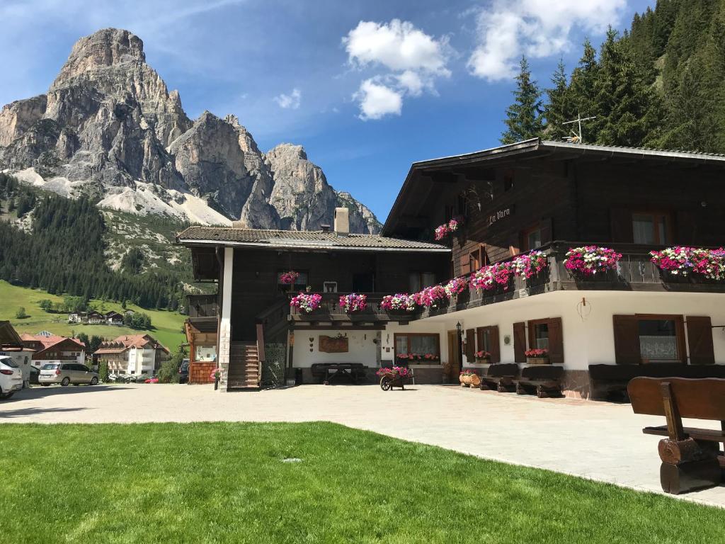 a building with flowers on it with a mountain at Garni La Vara in Corvara in Badia