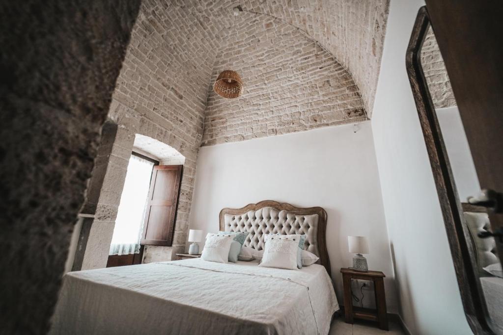 - une chambre avec un lit blanc et un mur en briques dans l'établissement Trullo Malvasia-Trulli Antì Charme & Relax, à Alberobello