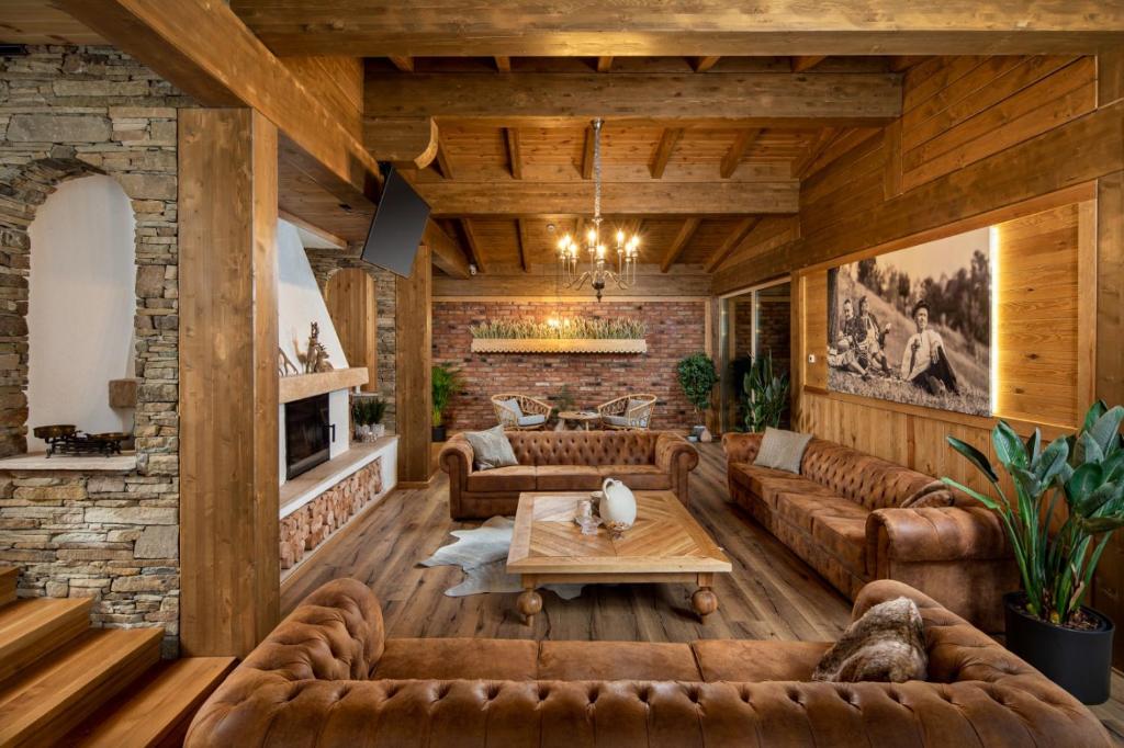 a living room with leather furniture and a brick wall at Zara Chalet in Bran