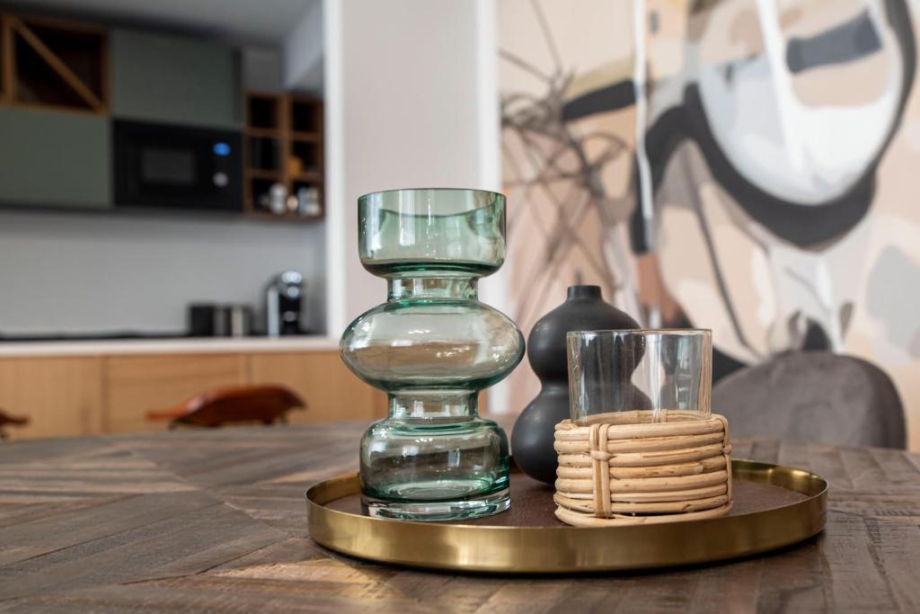 szklaną wazę na złotej płytce z kubkiem na stole w obiekcie Duett - Urban Rooms w Győr