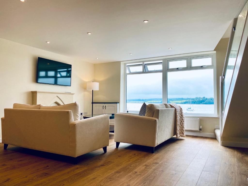 een woonkamer met 2 stoelen en een groot raam bij New home with stunning views of the Menai Straits in Llanedwen