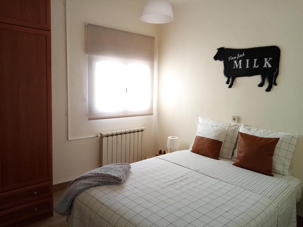 a bedroom with a bed with white sheets and a window at El Abuelo Paco in Cercedilla