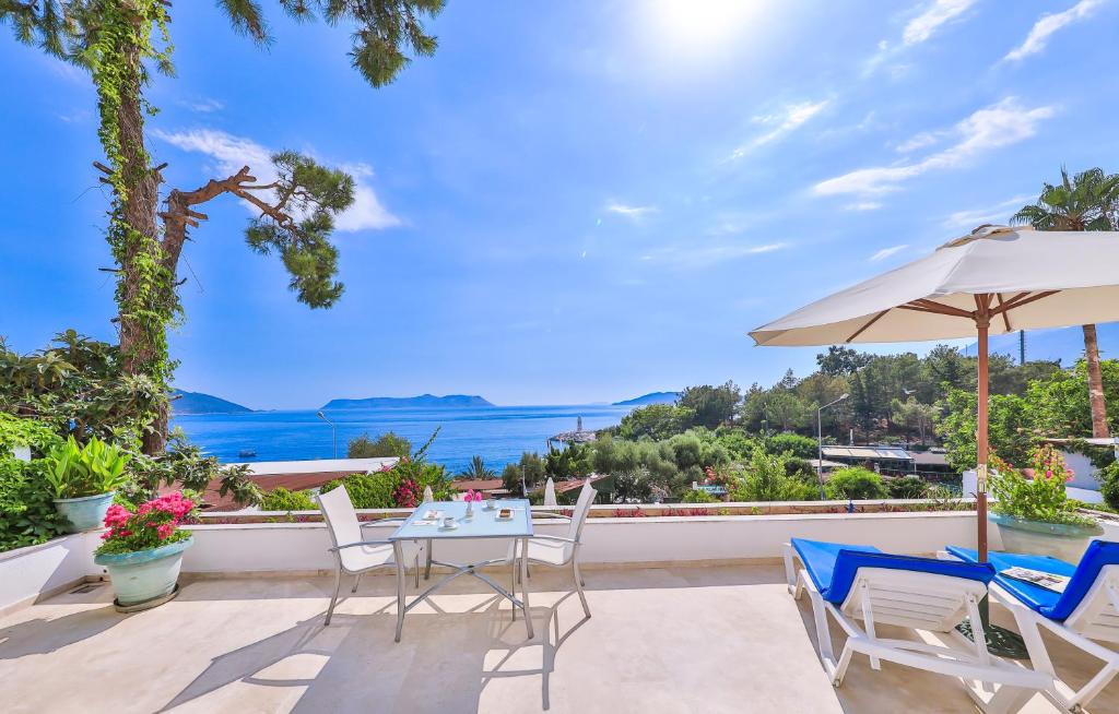 eine Terrasse mit einem Tisch, Stühlen und einem Sonnenschirm in der Unterkunft Gardenia Hotel in Kaş