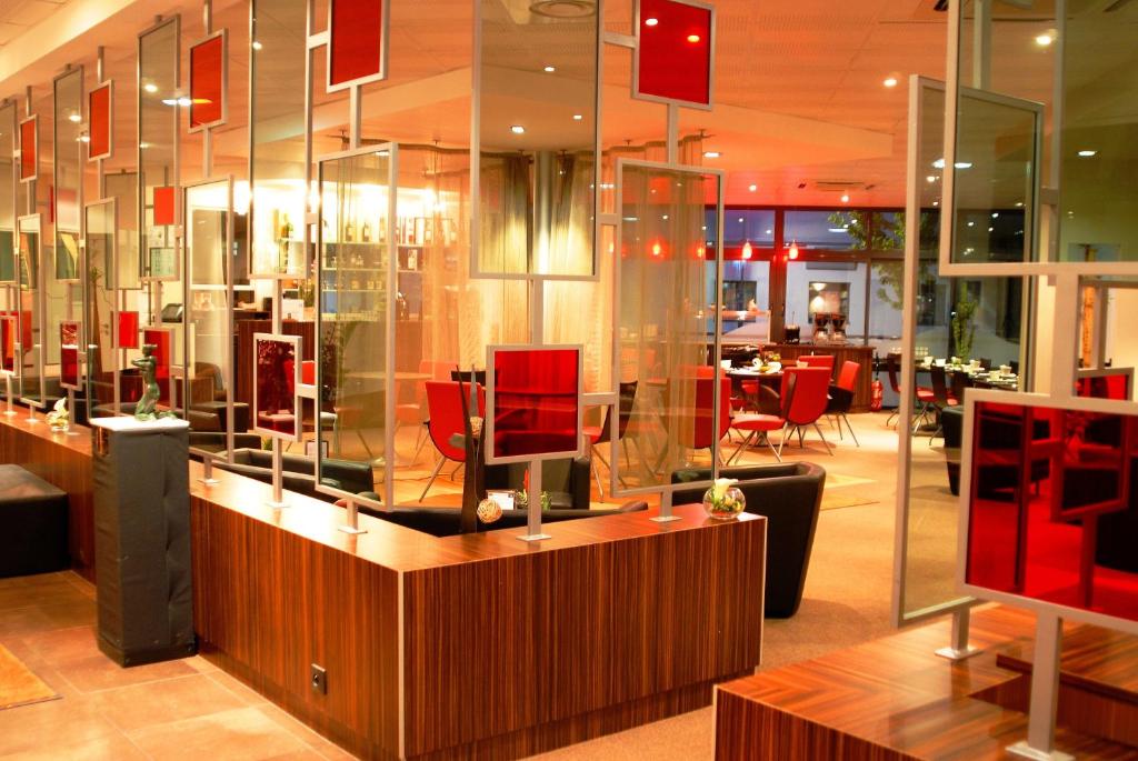 un restaurant avec des chaises rouges et un mur en verre dans l'établissement Hotel De Loire et Restaurant Les Bateliers, à Trélazé