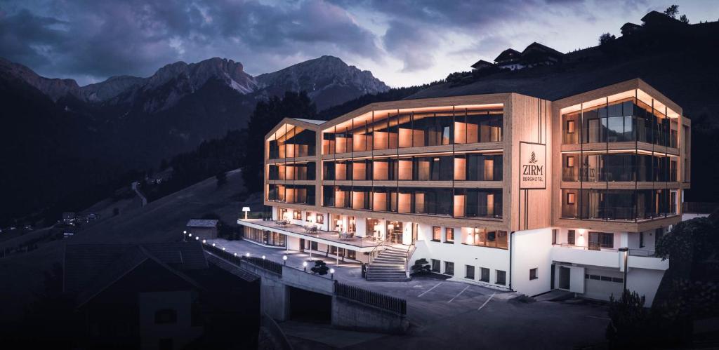 a large building with lights in front of a mountain at Kronplatz-Resort Berghotel Zirm in Valdaora