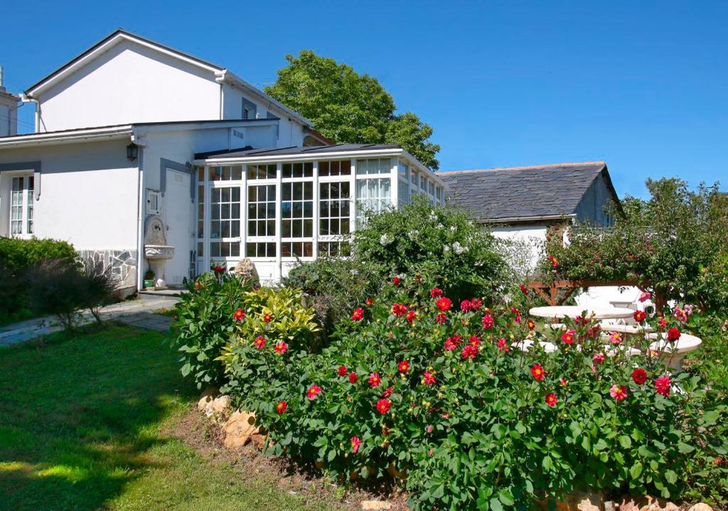 una casa con flores rojas en el patio en Casa Elena Turismo Rural, en Reinante