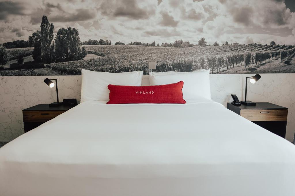 ein großes weißes Bett mit einem roten Kissen darauf in der Unterkunft Vinland Hotel and Lounge in Solvang