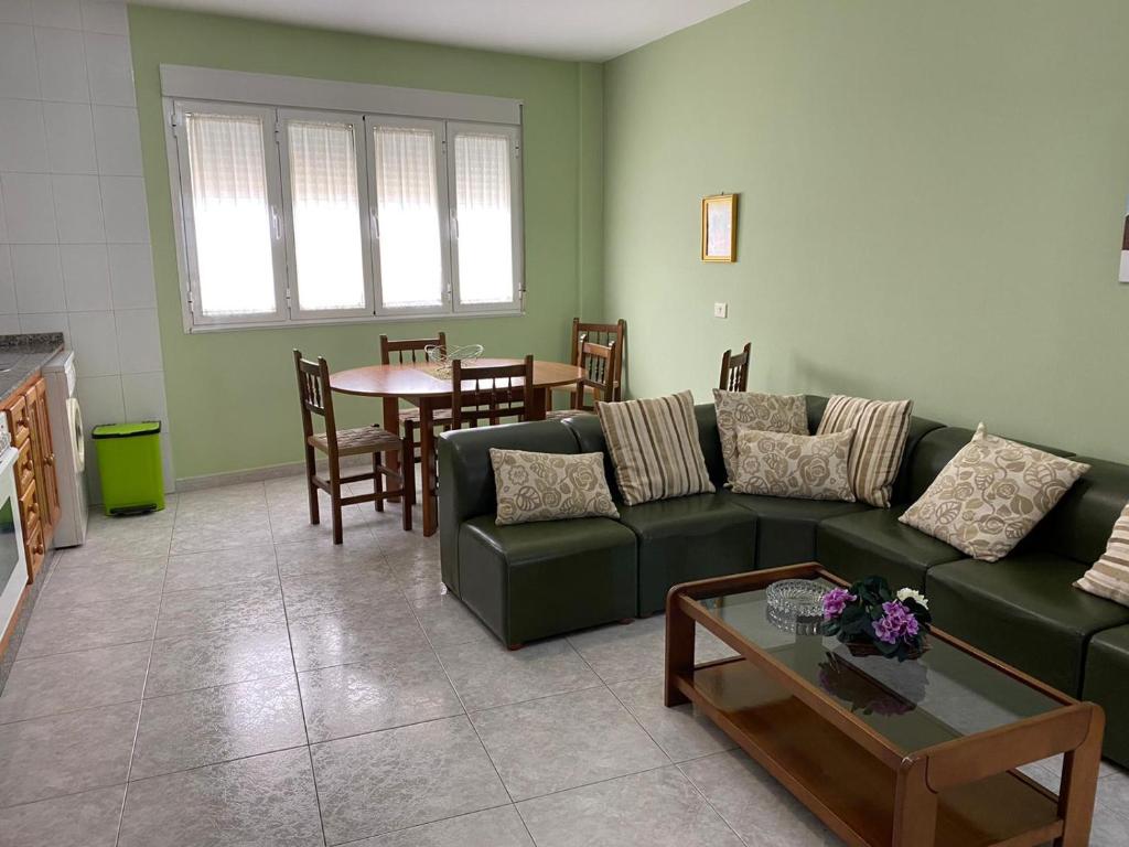 een woonkamer met een groene bank en een tafel bij APARTAMENTOS CAMIÑO DO RIO in O Grove