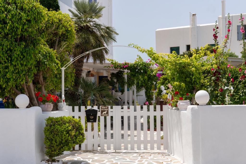una cerca blanca con flores y plantas frente a una casa en Ricos Two Bedroom House - Naoussa Paros, en Naousa