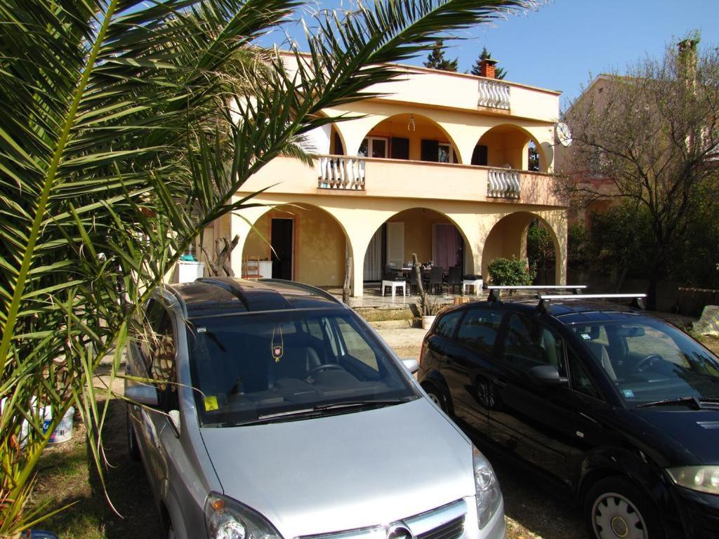 two cars parked in front of a house at Apartments REM in Novalja