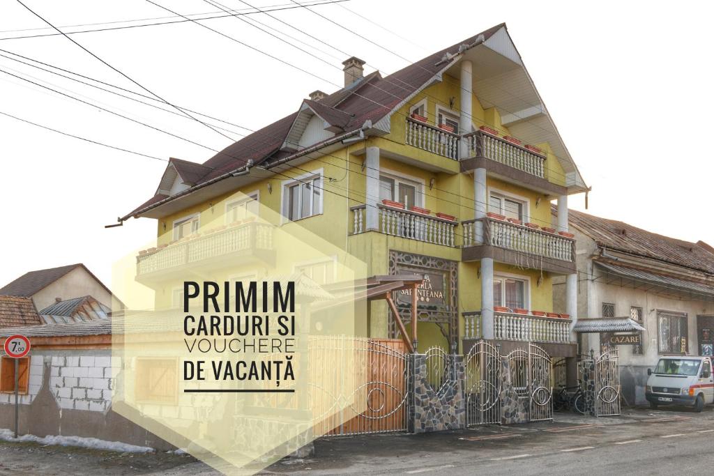 una casa amarilla con un cartel en el costado. en Vila Perla Sapanteana, en Săpînţa