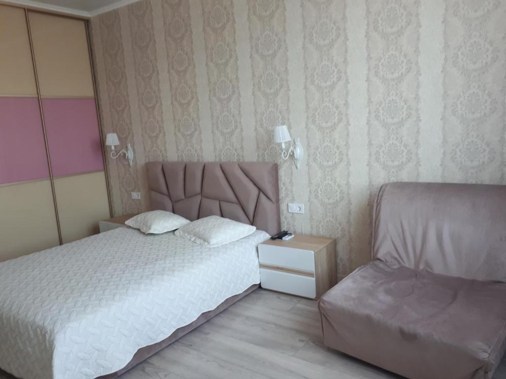 um pequeno quarto com uma cama e uma cadeira em Apartments Lutsdorf em Odessa