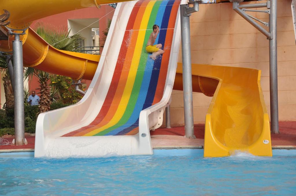 Sharm Bride Resort Aqua & SPA في شرم الشيخ: زحليقة ملونة في حمام السباحة مع شخص عليه