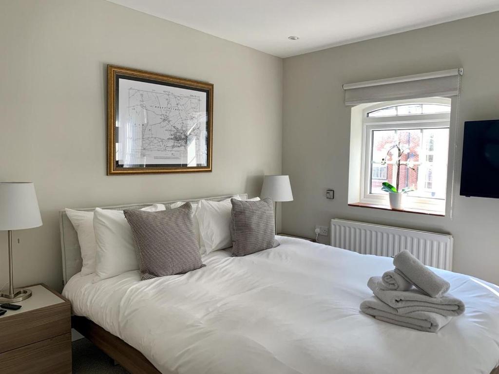 een slaapkamer met een wit bed en handdoeken bij Brewery Cottage in Abingdon