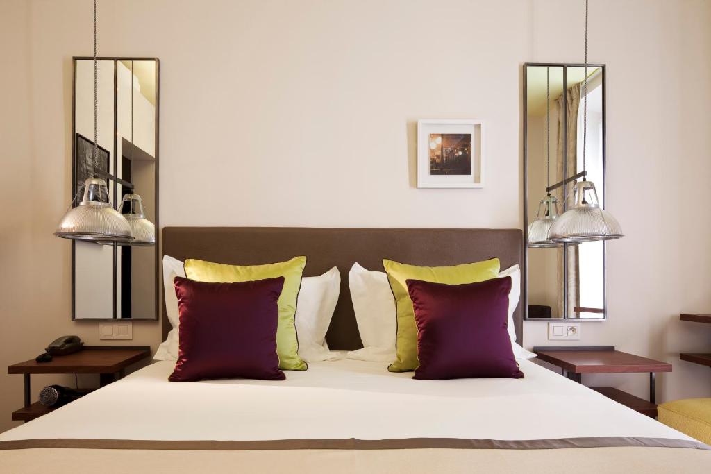 a bedroom with a large bed with red and yellow pillows at Hôtel Marais Bastille in Paris