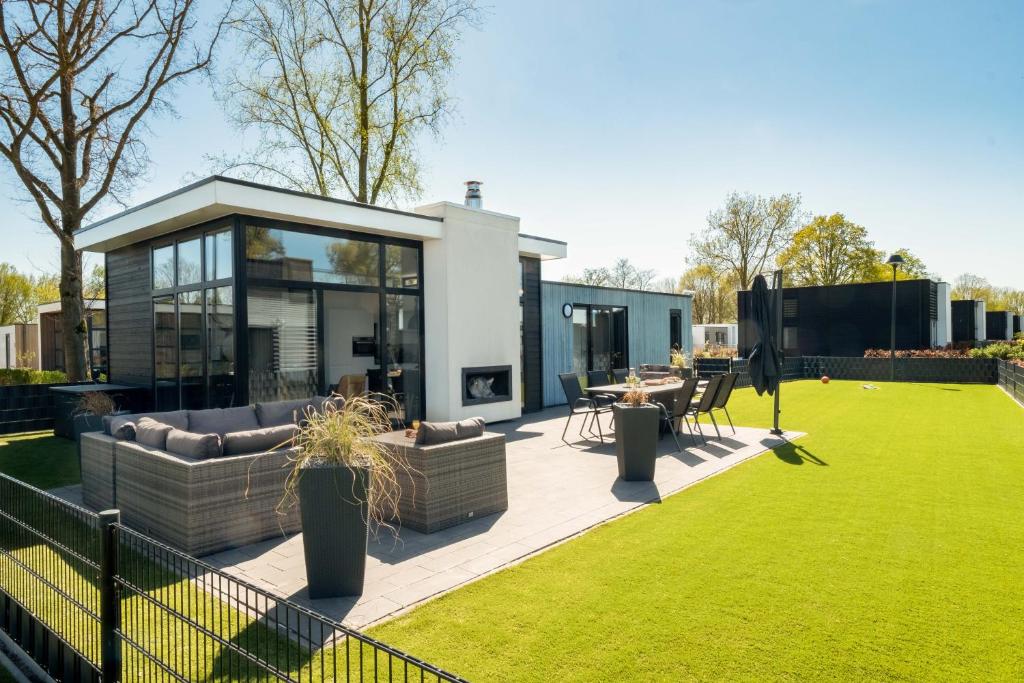 ein modernes Haus mit einer Terrasse und einer Liegewiese in der Unterkunft Cube Exclusive Plus mit Meerblick am Strand im EuroParcs Bad Hoophuizen in Hulshorst