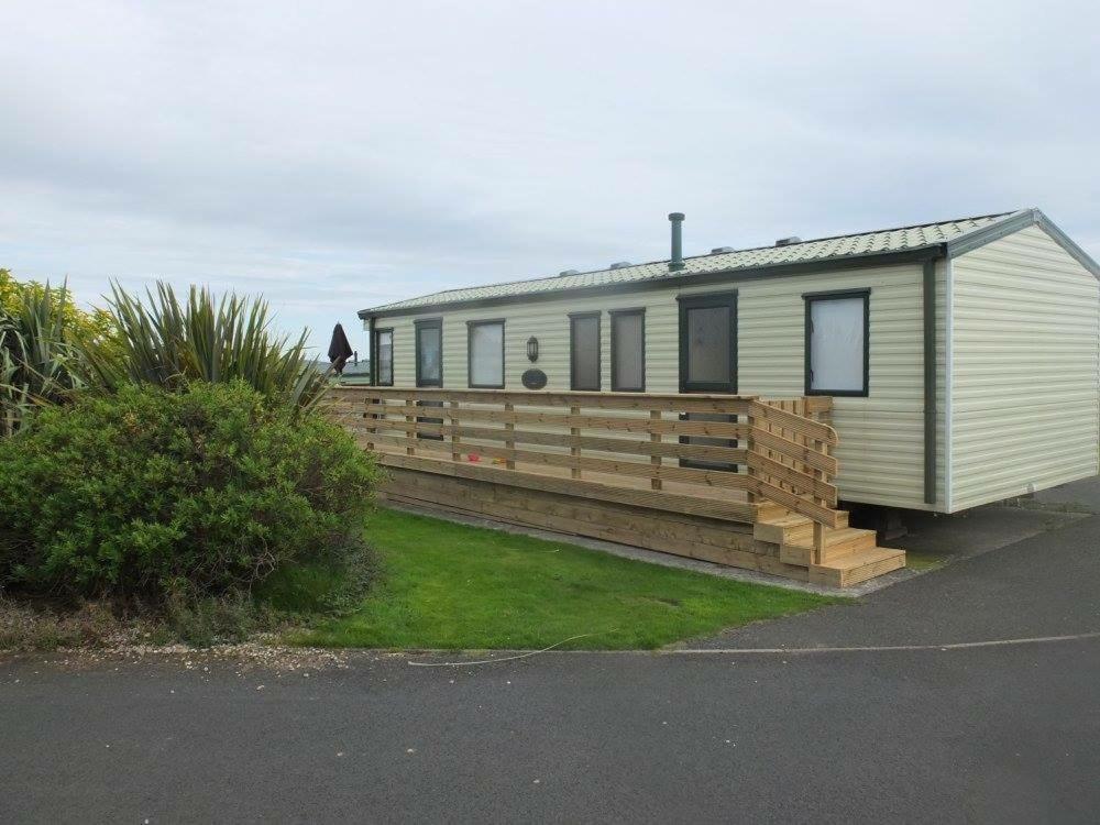 a mobile home with a large wooden deck at Wigbay Loch View 28 in Kirkcolm