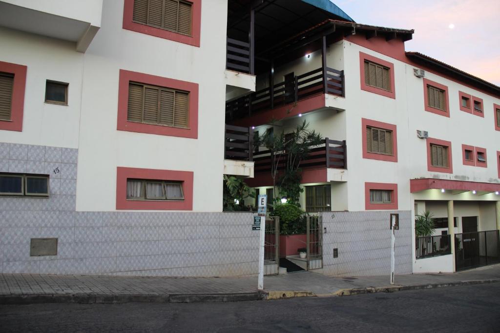 a white building with red windows and a street at Hotel São Lucas in Alfenas