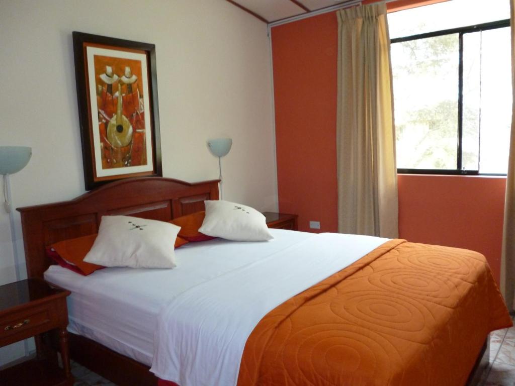 una camera da letto con un grande letto con lenzuola bianche e una finestra di Hotel San José a Piura