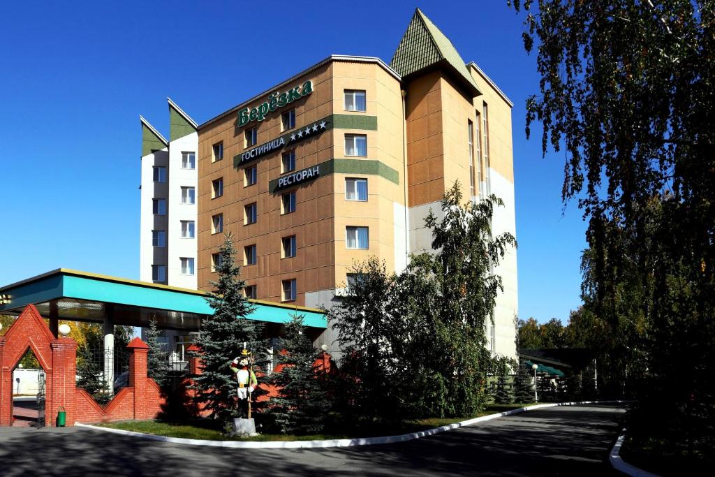 un hotel con un edificio con un árbol delante en Park Hotel Berezka, en Chelyabinsk