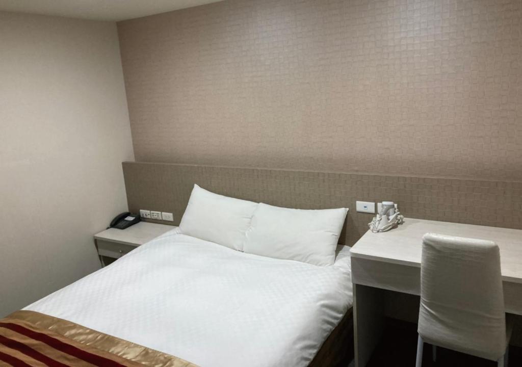 a hotel room with a bed and a table at Shun-yi Business Hotel in Chiayi City