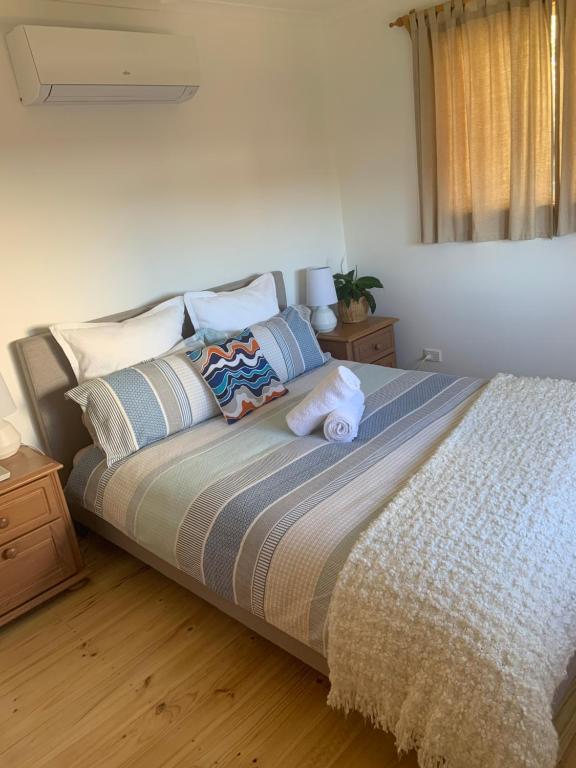 ein Schlafzimmer mit einem Bett mit Kissen und einem Fenster in der Unterkunft Moana Beach Sunset Holiday Accommodation A in Moana