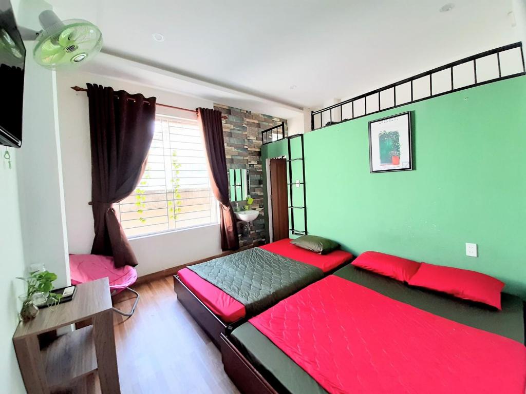 1 dormitorio con cama roja y pared verde en Homestay Xì Trum en Da Nang