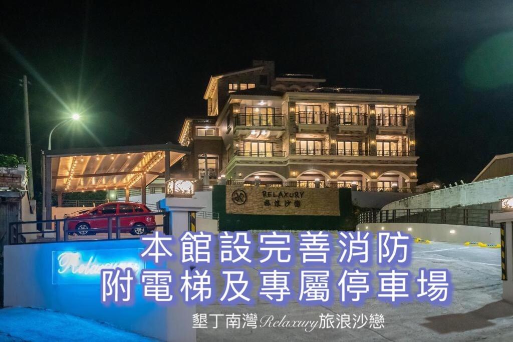 a sign in front of a building at night at 墾丁南灣Relaxury旅浪沙戀民宿 in Nanwan