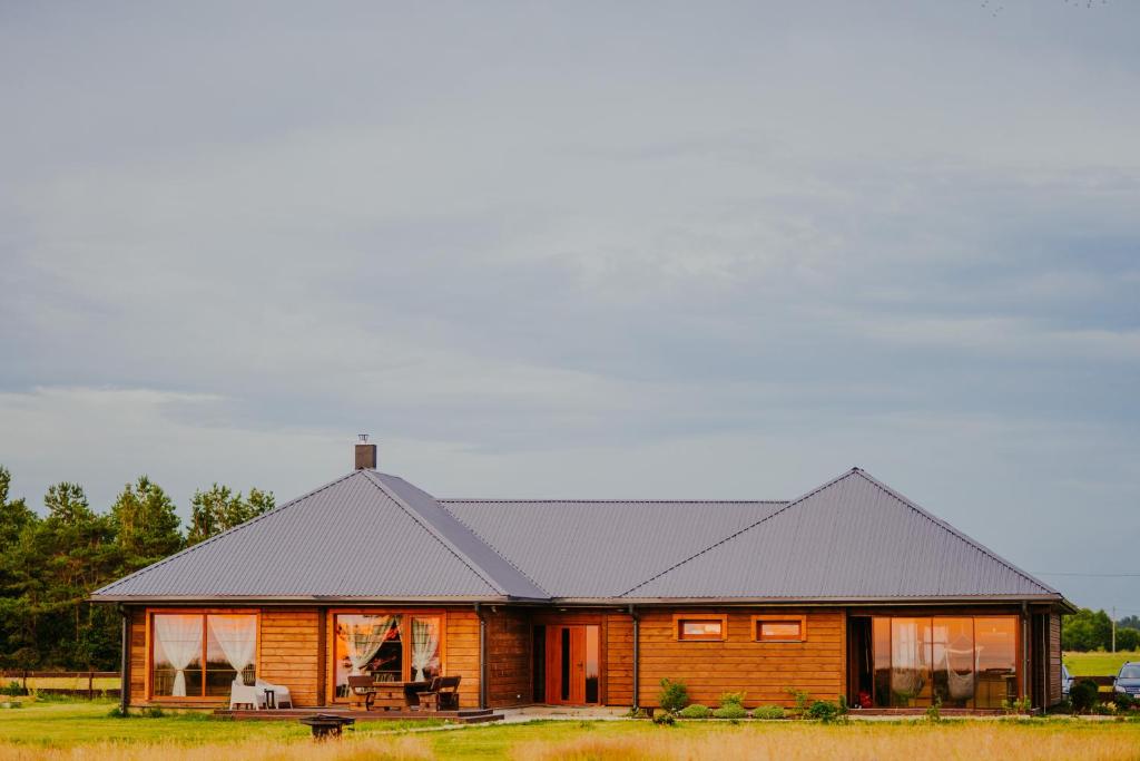 een blokhut met een zwart dak bij Salas Holiday Home in Jūrkalne