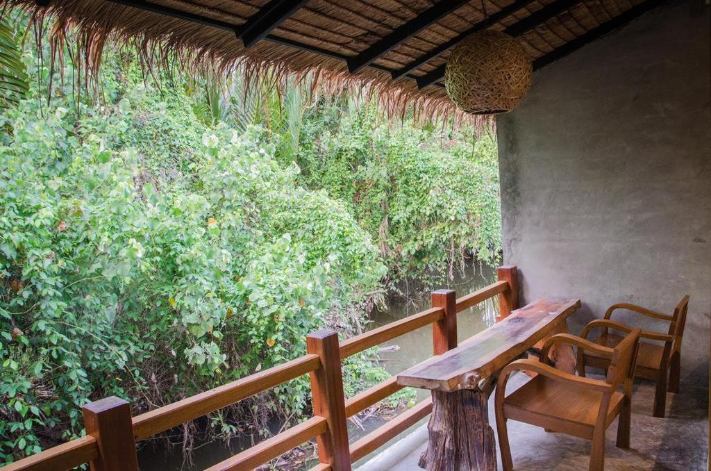 um alpendre com uma mesa de madeira, cadeiras e árvores em Ruean Thai Nai Bang by PANSAK Resort em Surat Thani