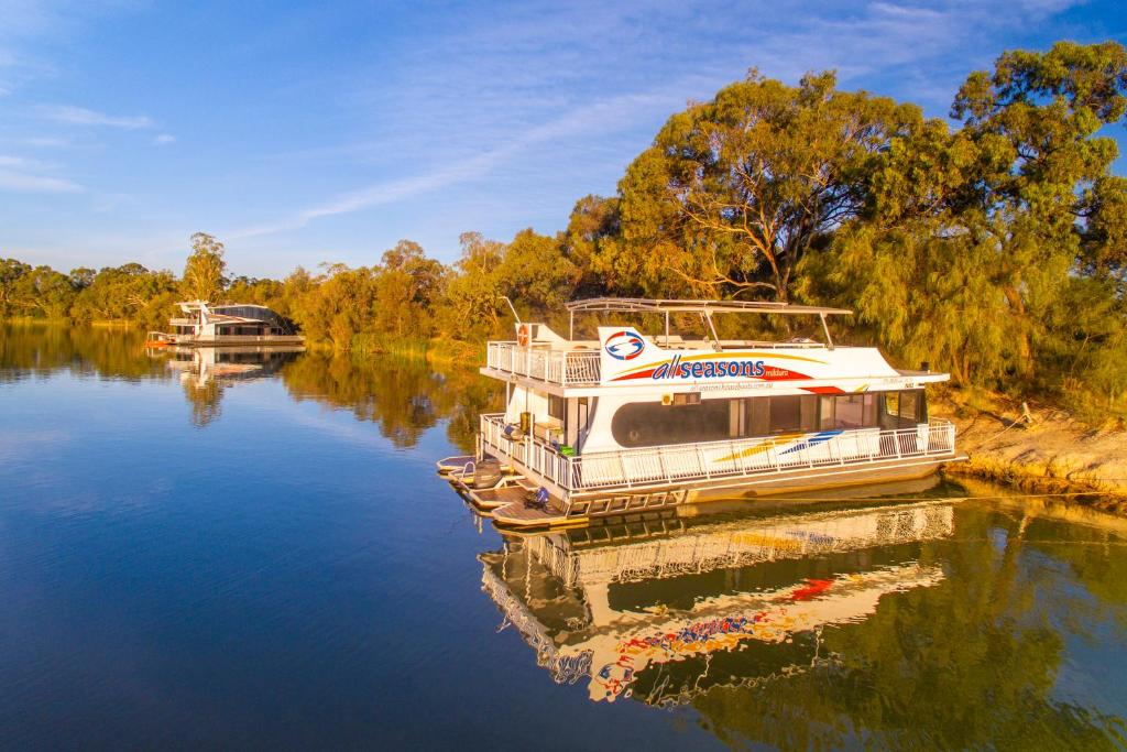 a boat is docked on a river at All Seasons Houseboats in Mildura