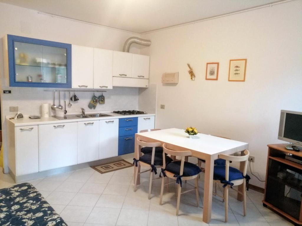 eine Küche mit weißen Schränken sowie einem Tisch und Stühlen in der Unterkunft Val di Luce Home in Abetone
