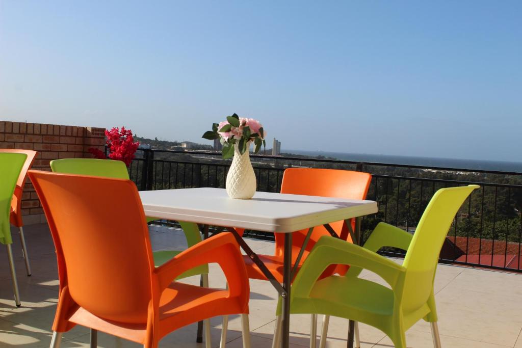 una mesa y sillas con un jarrón de flores en el balcón en Royal Ushaka Hotel Morningside, en Durban