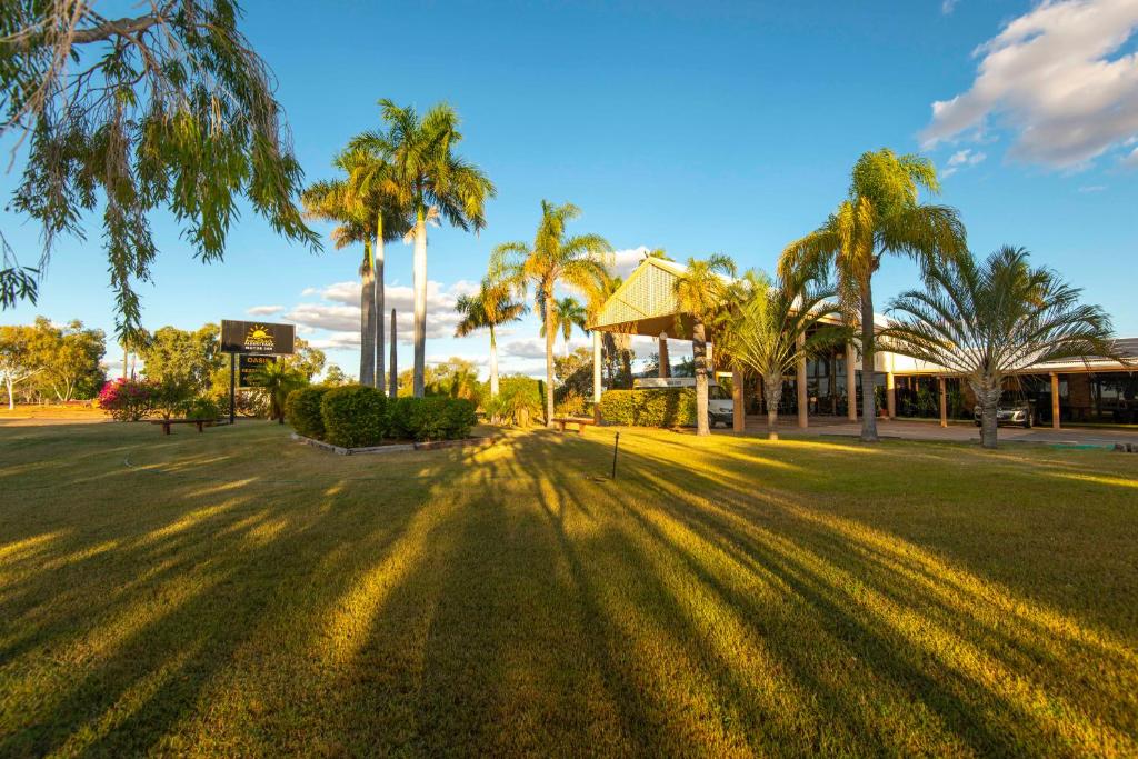 a park with palm trees and a building at Albert Park Motor Inn-KING BEDS-POOL-SHADED PARKING in Longreach