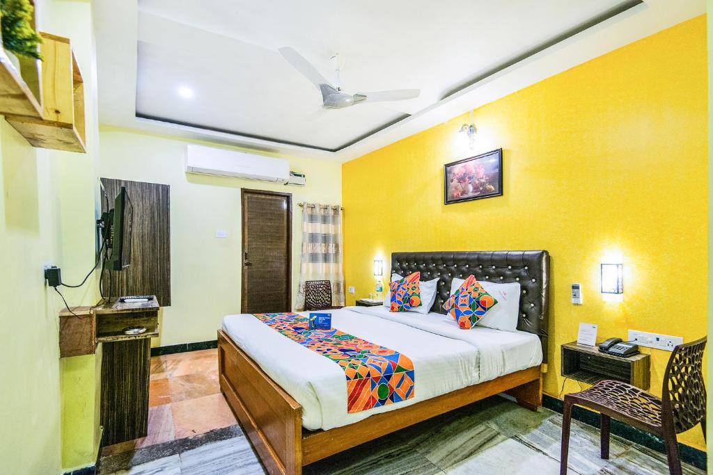 um quarto com uma cama e uma parede amarela em Royal Palace Marina em Chennai