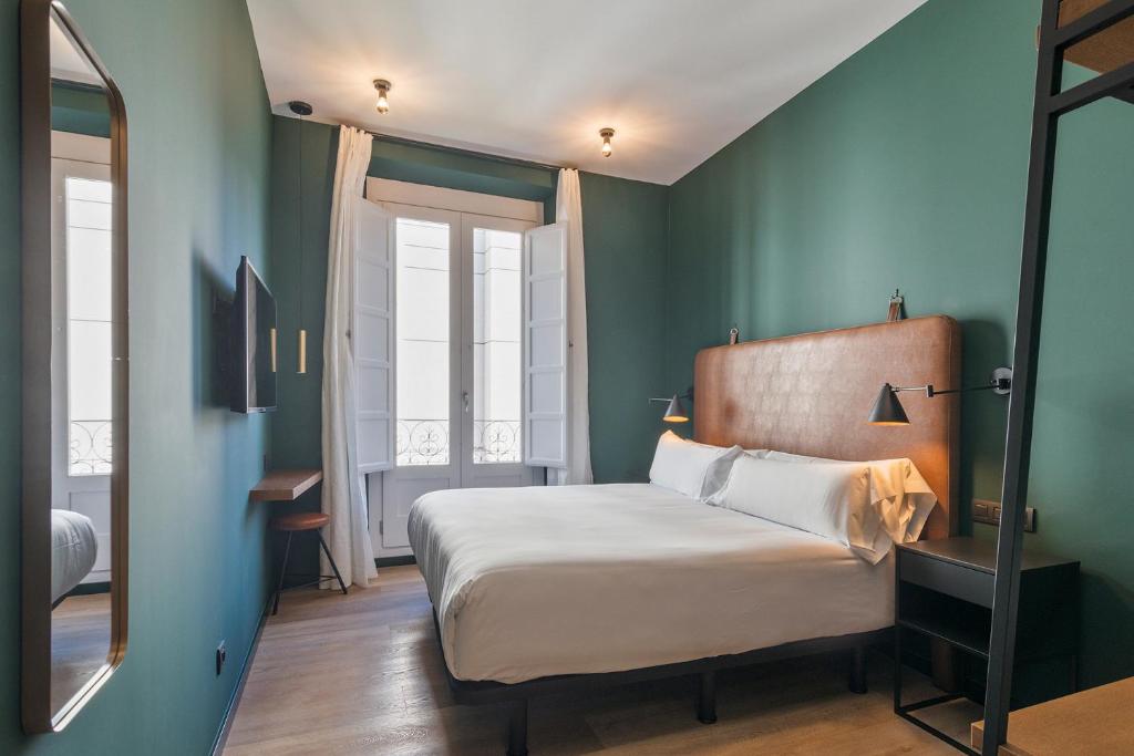 1 dormitorio con 1 cama grande y espejo en Uma Suites Atocha, en Madrid