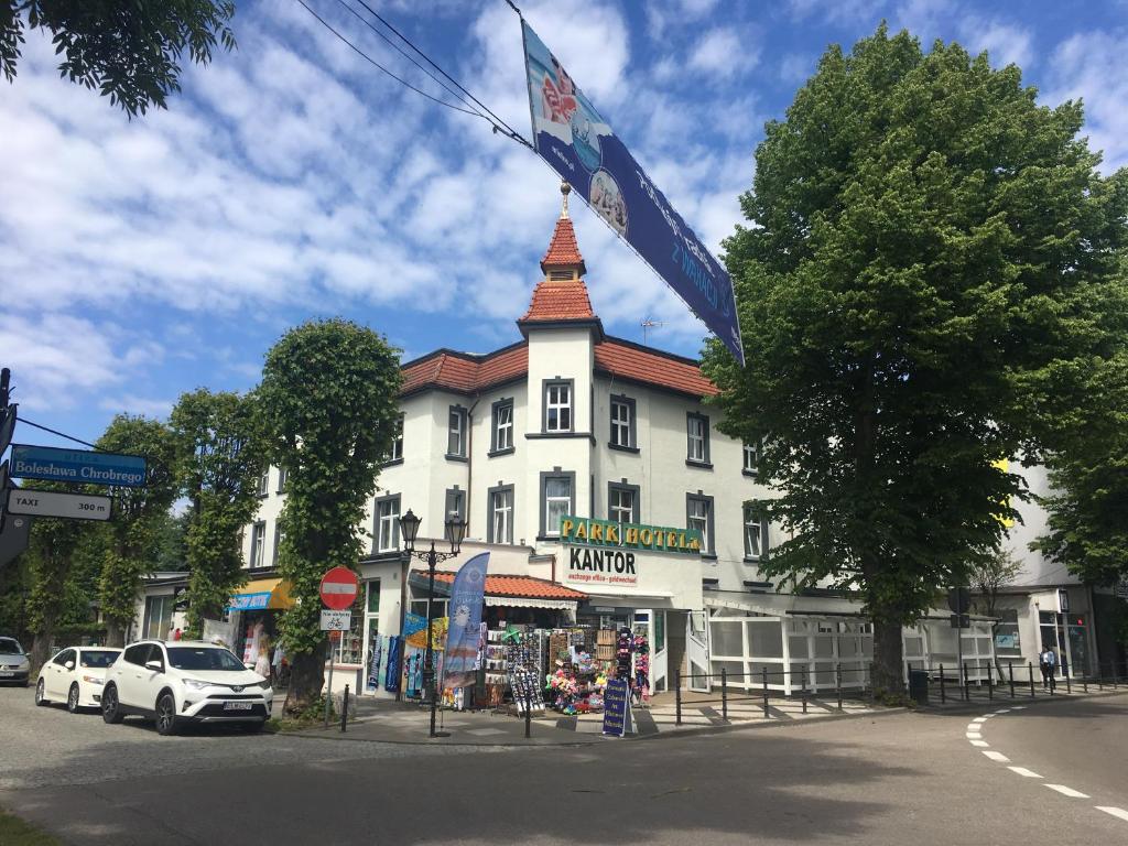 a large white building with a tower on a street at Park Hotelik II Piętro in Mielno