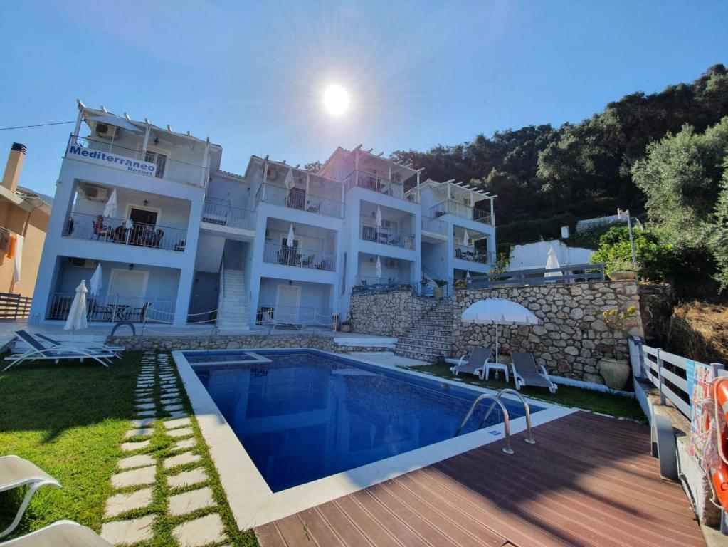 a villa with a swimming pool and a house at Mediterraneo Resort in Parga
